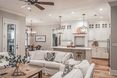 a living room filled with furniture and a kitchen in the backgroung area