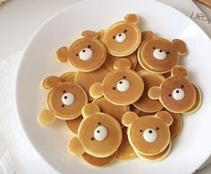 some pancakes with teddy bears on them are sitting on a plate next to utensils