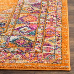 an orange area rug with multicolored designs on the bottom, and a wooden floor