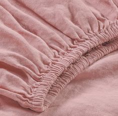 an unmade bed with pink linens on the sheets and pillow cases, close up