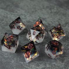 five clear dices with holographic numbers on them sitting on a gray surface