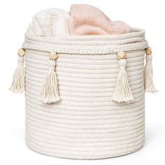 a large white basket with tassels on the sides and a pink blanket inside