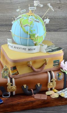 a cake made to look like suitcases with a globe on top and other items around it