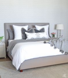 a bedroom with a bed, nightstands and lamps on either side of the bed