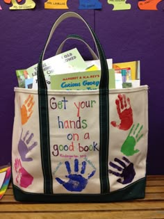 a bag with hand prints on it sitting on top of a wooden table in front of a purple wall