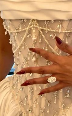 a close up of a person's hand with rings on her finger and dress in the background