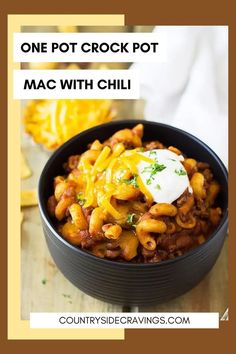 one pot crock pot mac and cheese with chili in a black bowl on a wooden table