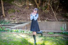 a young woman is standing in the grass and talking on her cell phone while wearing knee high boots