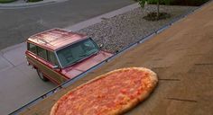 a pizza sitting on top of a wooden table next to a red car and the words, i threw my pie for you