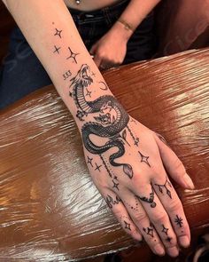 a woman's hand with a tattoo on it and stars in the sky above her