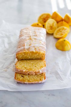 two slices of lemon pound cake sitting on top of wax paper next to sliced lemons