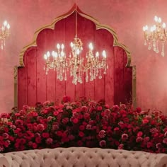 a couch and chandelier in a room with pink walls, red flowers on the floor