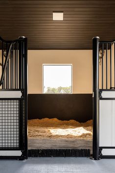 an open barn door leading into a room with hay in the floor and on the ground