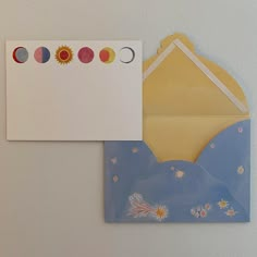 an open envelope with a card attached to it next to a piece of paper on the wall