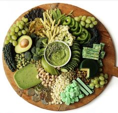 a wooden platter filled with different types of vegetables and dip surrounded by other food items