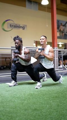 two men doing squats on the ground in a crossfit gym with people watching