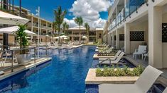 an outdoor swimming pool with lounge chairs and umbrellas next to the hotel's entrance