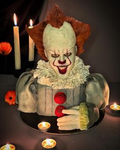 a creepy clown cake with candles around it