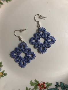 a pair of blue earrings sitting on top of a white plate