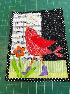 a red bird sitting on top of a piece of fabric next to a green cutting board