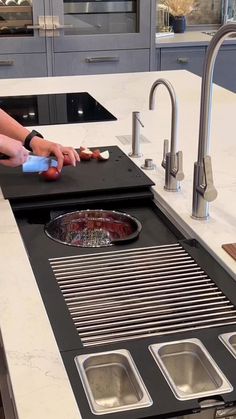 a person is using a sponge to clean a sink in a kitchen with stainless steel appliances