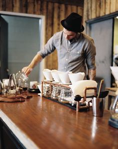 a man standing at a counter preparing coffee