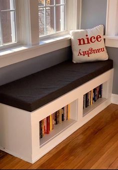 a white bench with books on it in front of a window