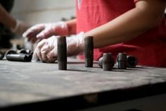 two people are working on some metal parts