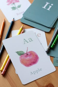 some cards that are on a table with pens and pencils next to each other