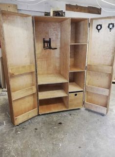 an open wooden cabinet in a garage with the doors closed and shelves missing from it