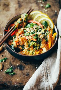 a bowl filled with food and chopsticks on top of a wooden cutting board