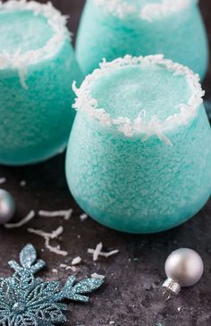 three glasses filled with blue colored liquid and snow flakes on top of a table