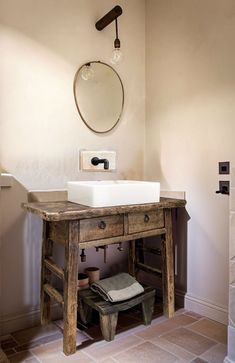 a bathroom sink sitting under a mirror next to a wooden table