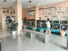 a woman is sitting on a bench in front of washers and dryer machines