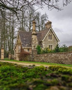 an old stone house with moss growing on the front and side walls, surrounded by trees