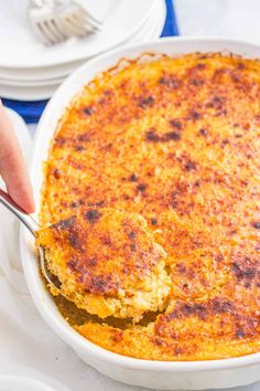 a person holding a spoon in a casserole dish