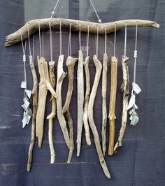 driftwood is hanging on the wall with beads and shells attached to it's sides