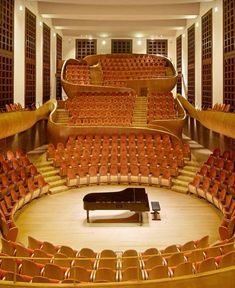 an empty auditorium filled with red seats and a piano