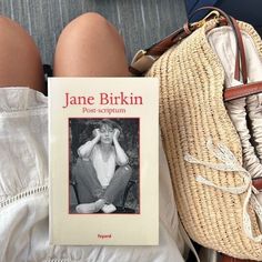 a book sitting on top of a woman's lap next to a handbag