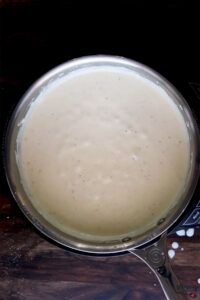 a pan filled with liquid sitting on top of a wooden table next to a spoon