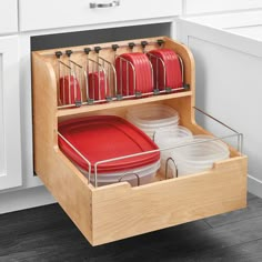 an open drawer in a kitchen filled with red pots and pans