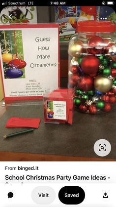 there is a glass jar with ornaments in it next to a sign that says guess how many ornaments are on the table