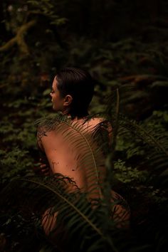 a naked woman standing in the woods surrounded by ferns