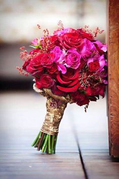 a bouquet of red and pink flowers sitting on top of a wooden table