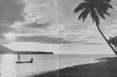 an old black and white photo of two people in a boat on the water near a palm tree