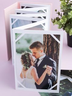 a couple kissing in front of a tree with their wedding photos on it and the card is folded