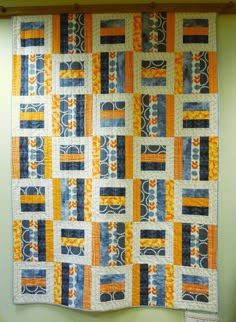 an orange and blue quilt hanging on the wall