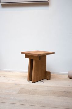 a wooden table sitting on top of a hard wood floor next to a white wall