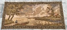 an old tapestry with boats and windmills on the river in front of a stone wall