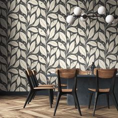 two chairs and a table in front of a wall with leaves on it, against a wooden floor